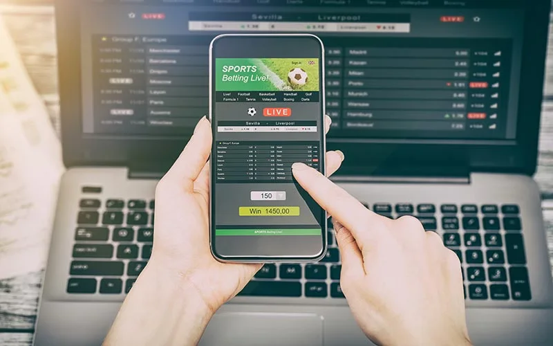 Dedicated Bangladeshi supporter placing fast bets on mobile and laptop during a tense live cricket game