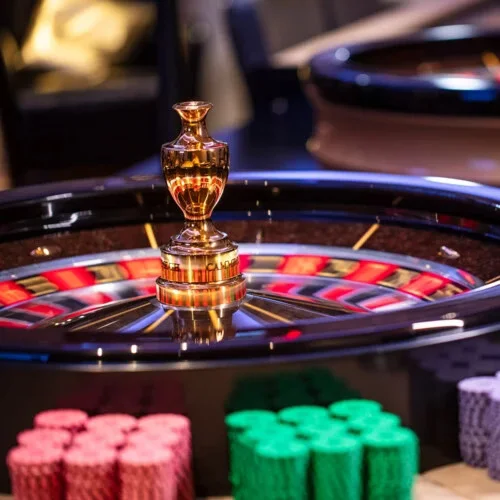 Contemporary laptop screen bursting with spinning lucky symbols wrapped in vivid casino light effects and energetic glow, showcasing the magnetic pull of CROWNBD games in Bangladesh
